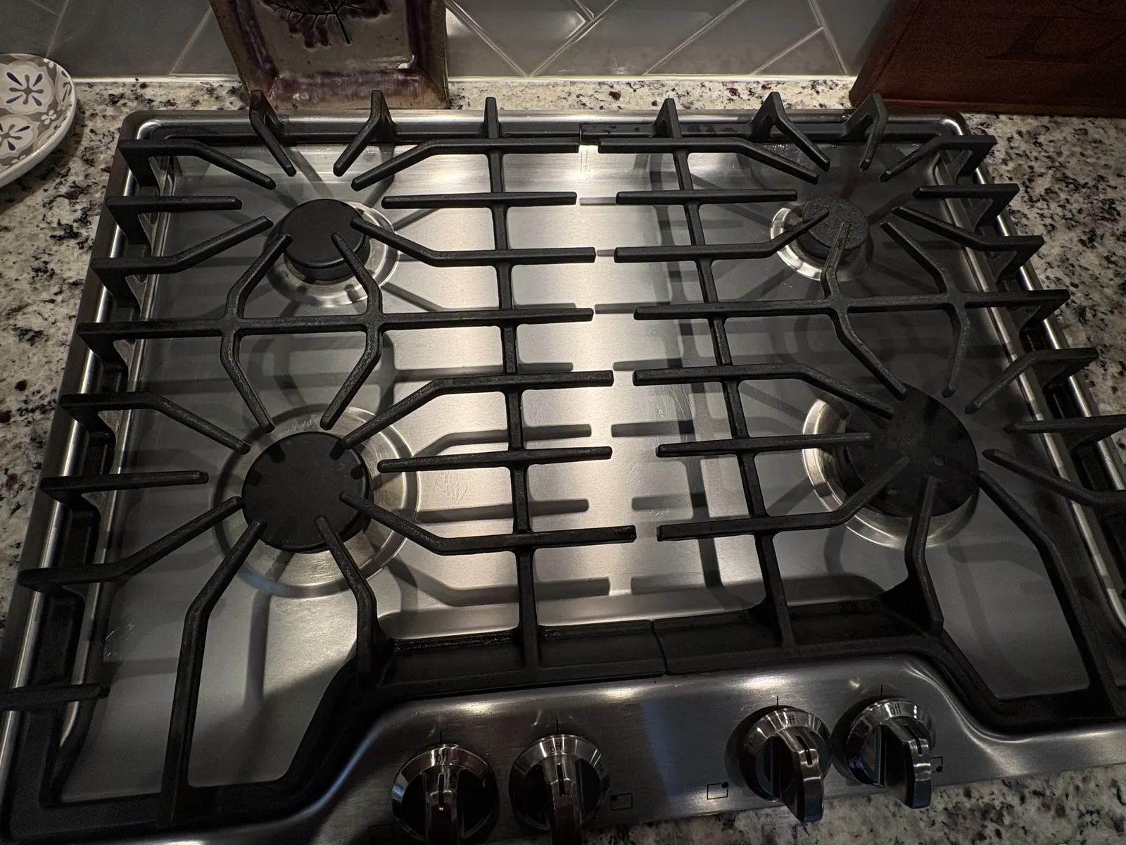 Dirty stovetop burner grates before a deep clean